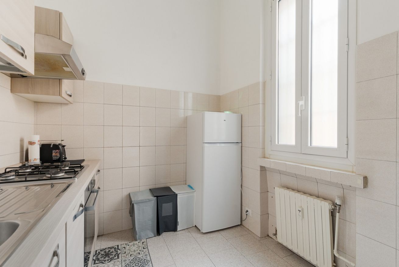 A compact kitchen with a stove, refrigerator, and a window.