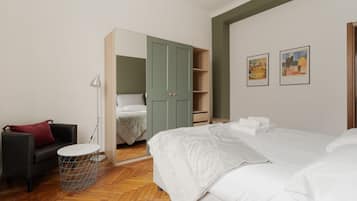 Une chambre à coucher comprenant un lit, une armoire, une chaise, une lampe et deux tableaux encadrés accrochés au mur.