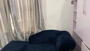A small room with a bed, a sofa, a wardrobe, and a curtain. - Century 24 Hotel and Suites  (Lagos)