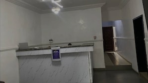 A reception desk with a sign, a ceiling light fixture, and a staircase in the background. - Century 24 Hotel and Suites  (Lagos)