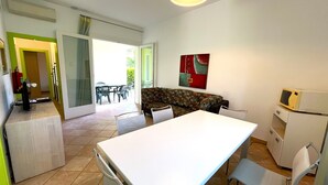 Ett kompakt bostadsutrymme med en matplats, ett litet kök och en soffa.