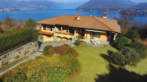 A house with a tiled roof overlooking a lake and mountains.