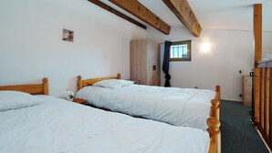 Een slaapkamer met twee houten bedden, een kledingkast en een raam met gordijnen.