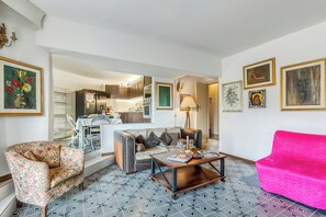 A living room with a patterned floor, a sofa, a coffee table, and a bright pink couch. - Thai House Private Parking Near Lake (Toscolano Maderno)