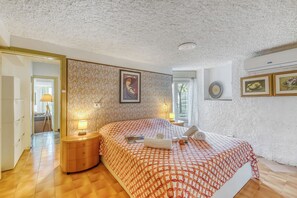 A bedroom with a patterned bedspread, a bedside table with a lamp, and a painting on the wall. - Thai House Private Parking Near Lake (Toscolano Maderno)