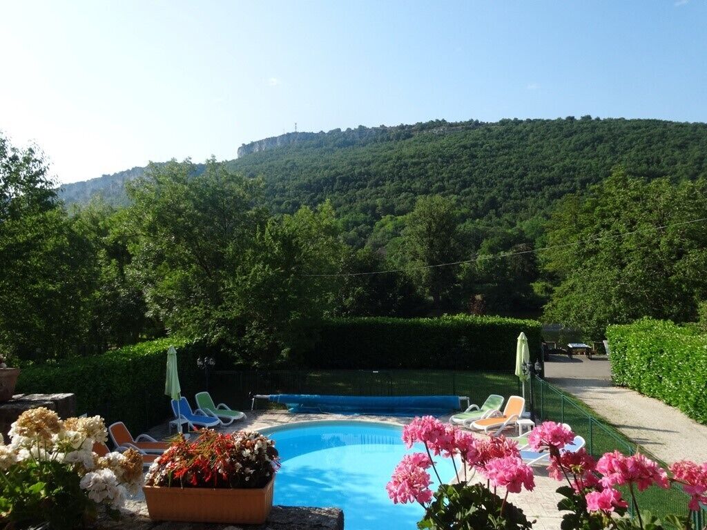 Une piscine entourée de chaises longues, de verdure et d’un paysage vallonné.