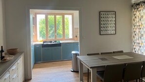 Eine moderne Küche mit Fenster, ein Essbereich mit Tisch und Stühlen sowie ein Mülleimer.