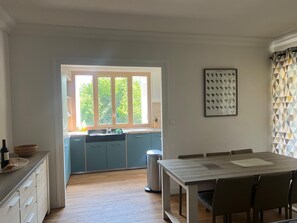 Eine moderne Küche mit Fenster, ein Essbereich mit Tisch und Stühlen sowie ein Mülleimer.