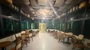 A restaurant with a central seating area, tables, and chairs arranged around it. - Palette Sunset Garden Tam Coc (Ninh Binh)