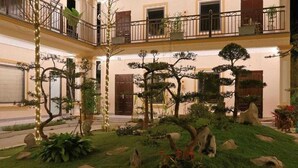 A multi-level building with a garden courtyard featuring bonsai trees and rocks. - Palette Sunset Garden Tam Coc (Ninh Binh)