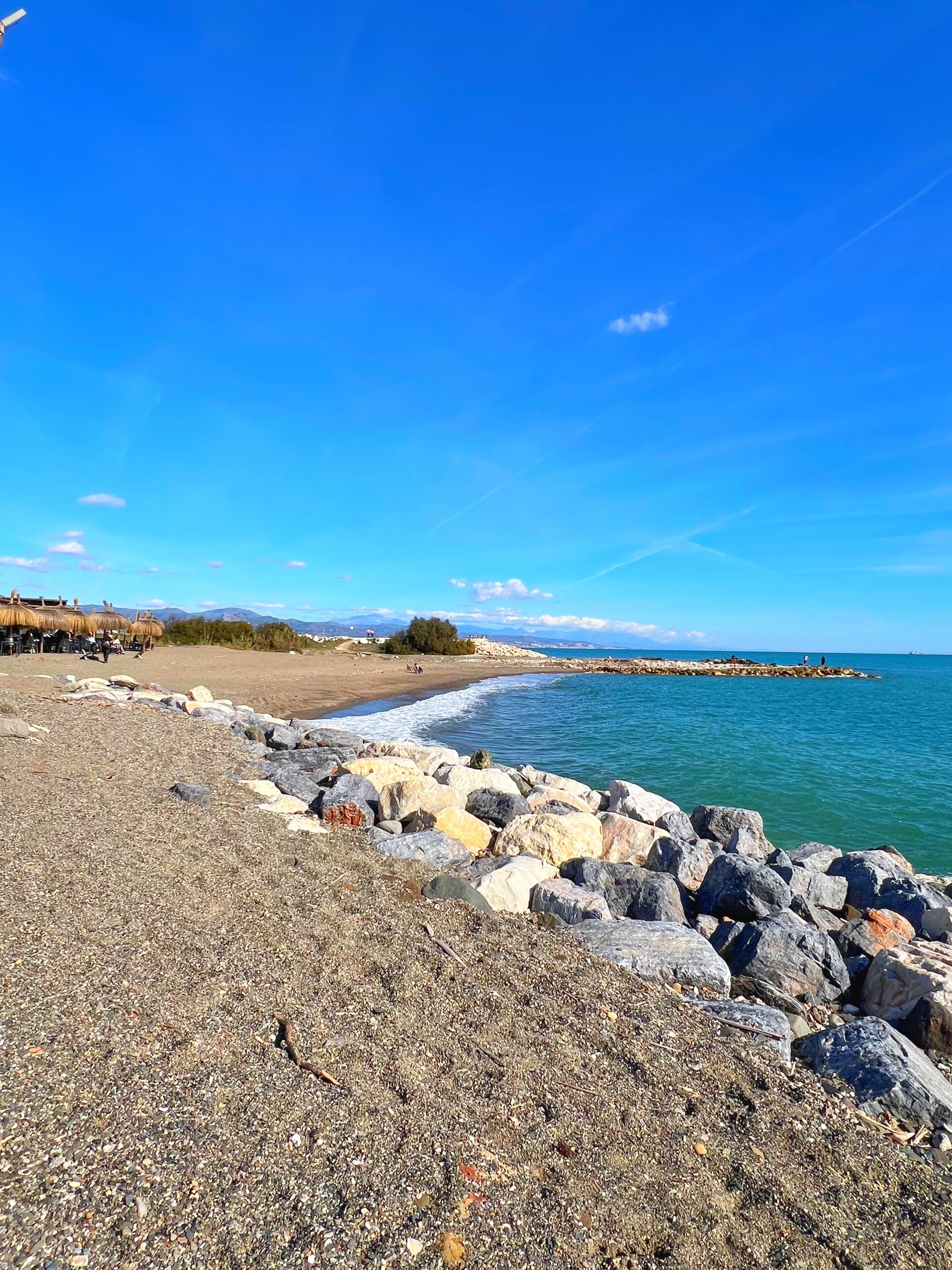 A rocky beach with a clear blue sky and calm sea.