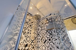 A shower with a geometric tile pattern and a glass enclosure. - Lovely Rhome  apartment near Vatican (ROMA)