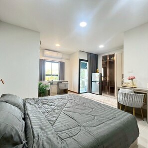Ein modernes Schlafzimmer mit einem großen Bett, einem Schreibtisch und einer Glastür zum Balkon.