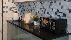 Une cuisine dotée d’un plan de travail noir, d’un grille-pain, d’une machine à café et d’un crédence décorative.