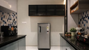 Une cuisine moderne dotée d’un réfrigérateur en acier inoxydable, de meubles de couleur noire et d’un dosseret de carrelage à motifs géométriques.