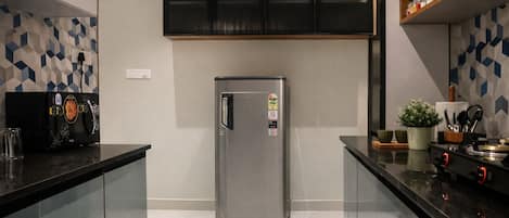 Una cocina moderna con refrigerador de acero inoxidable, gabinetes negros y un salpicadero de azulejos geométricos.