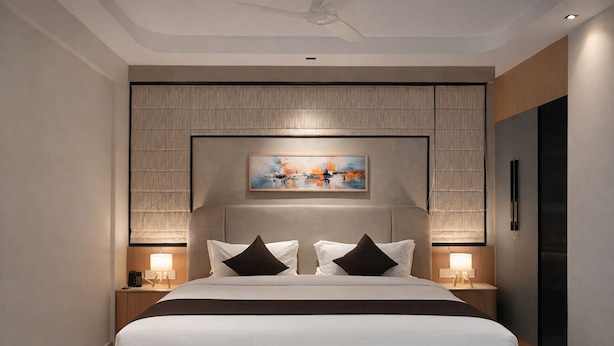 Une chambre d’hôtel moderne avec un grand lit, deux tables de chevet, un ventilateur de plafond et un tableau au-dessus du lit.