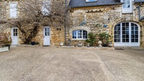 A stone building with a gravel driveway, arched windows, and a door.