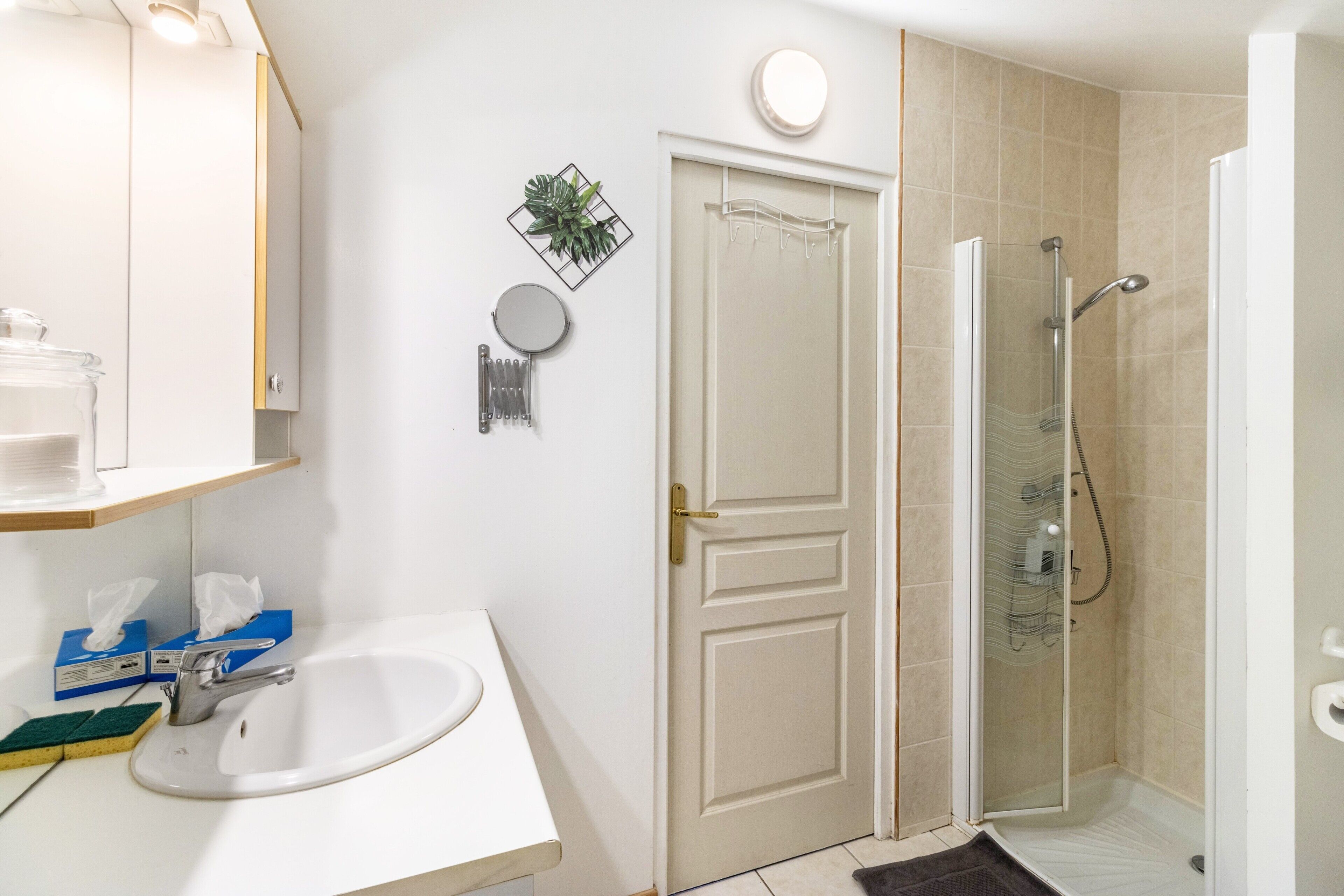 Un baño con lavamanos, espejo, toallero, ducha y puerta.