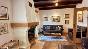 Una sala de estar acogedora con chimenea, piso de madera, un sofá y una mesa de centro.