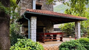 Un edificio rústico de piedra con techo de tejas y un banco de madera en la fachada.