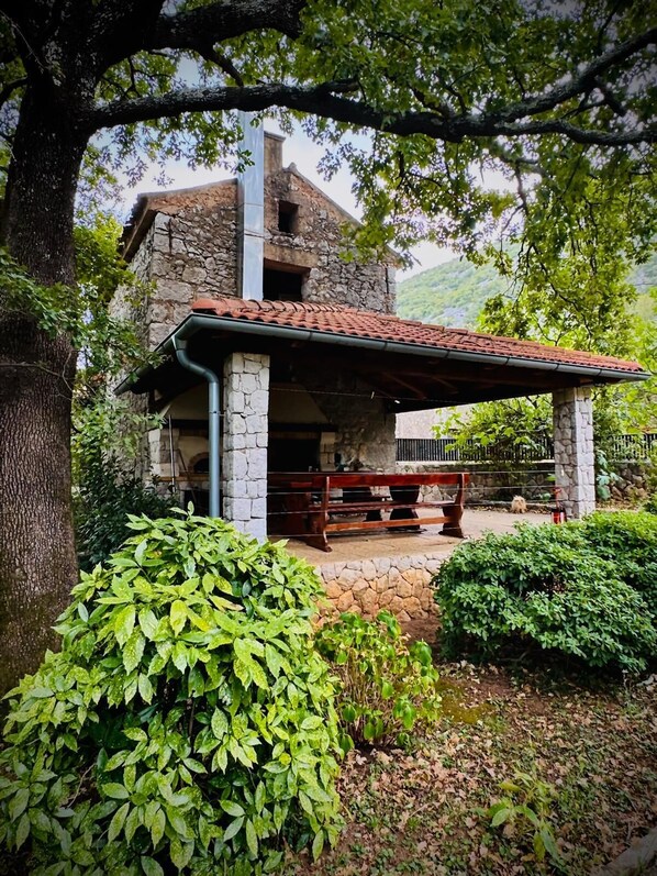 A rustic stone building with a tiled roof and a wooden bench in front. - Kuća Zelenog Sna (Tribalj)