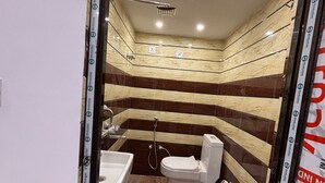 Ein Badezimmer mit Dusche, Toilette und Waschbecken, das sich durch gestreifte Wände und Holzböden auszeichnet.