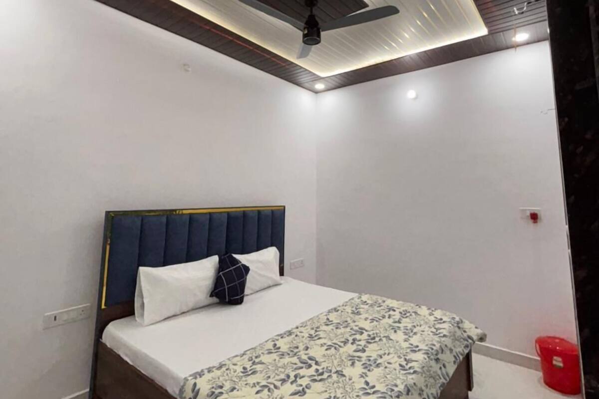 Een slaapkamer met een bed, een plafondventilator en een rode emmer.