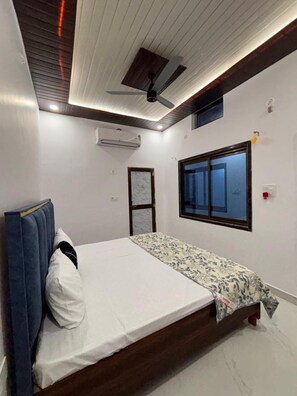 Een slaapkamer met een bed, een plafondventilator, een airconditioning en een raam en een deur.
