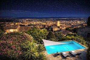A nighttime view of a cityscape with a swimming pool and lounge chairs. - Villa Janna in Hyères - Ocean View & Private Pool (Hyères)