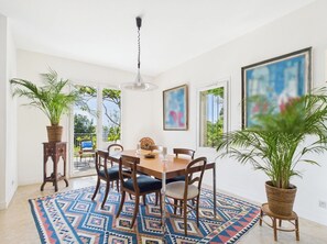 A dining area with a round table, six chairs, a patterned rug, and two potted plants. - Villa Janna Hyères-Sea view & private pool (Hyères)