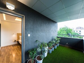 A modern hotel room with a balcony, a wooden floor, and a row of potted plants against the wall. - Townhouse MG Road (Bengaluru)