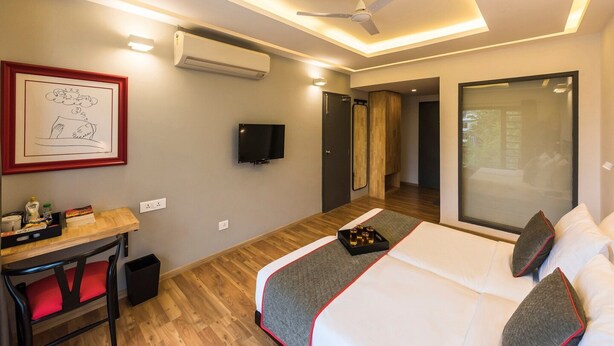 Una habitación de hotel moderna con una cama, un escritorio, una silla, un televisor de pantalla plana y un ventilador de techo.