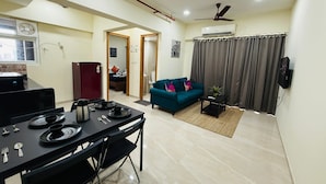 Una sala moderna con comedor, un sofá color turquesa y un ventilador de techo.