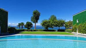 Une piscine à l’eau d’un bleu cristallin, entourée d’une végétation luxuriante et bien entretenue, avec vue sur la mer.