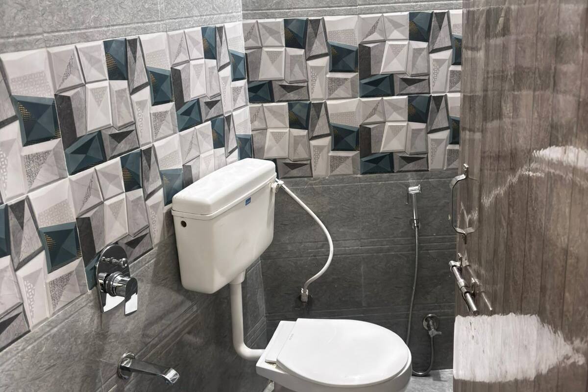 Une salle de bain moderne équipée de toilettes, d’un bidet et d’une douche. Les murs sont recouverts de carreaux aux motifs géométriques.