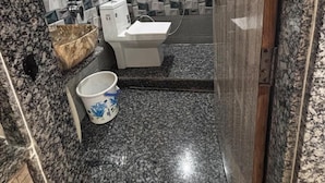 A bathroom with a toilet, a sink, and a shower area. - Hotel New Sun n rock (Mount Abu)