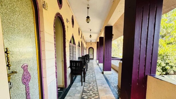 A corridor with patterned flooring, arched doorways, and a bench. - Hotel New Sun n rock (Mount Abu)