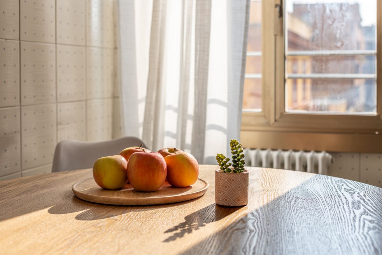 Une table en bois sur laquelle se trouve une assiette de pommes et une plante en pot.