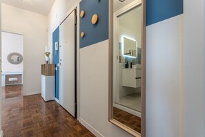A hallway with wooden flooring, a blue and white wall, and a glass door leading to a bathroom. - LUMINOSO APPARTAMENTO AL PIGNETO (ROMA)