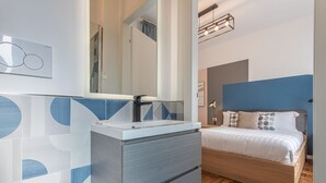 A modern bedroom with a bed, a bedside table, and a mirror. - LUMINOSO APPARTAMENTO AL PIGNETO (ROMA)