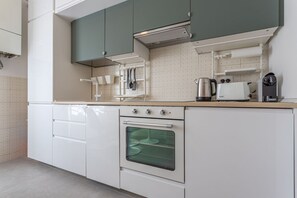 A modern kitchen with white cabinets, a built-in oven, and a coffee machine. - LUMINOSO APPARTAMENTO AL PIGNETO (ROMA)