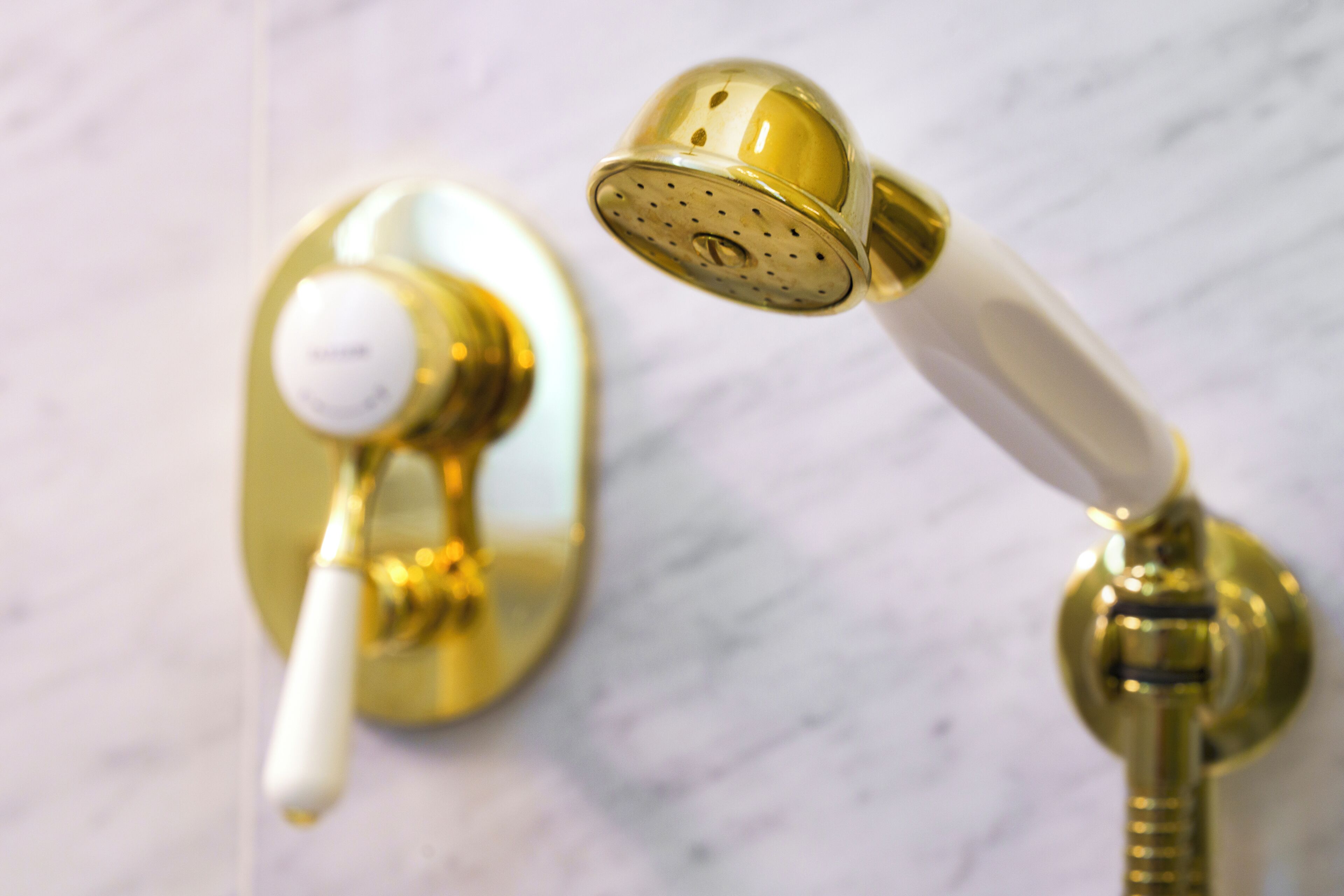 A bathroom with a gold-colored shower head and faucet, mounted on a marble surface.