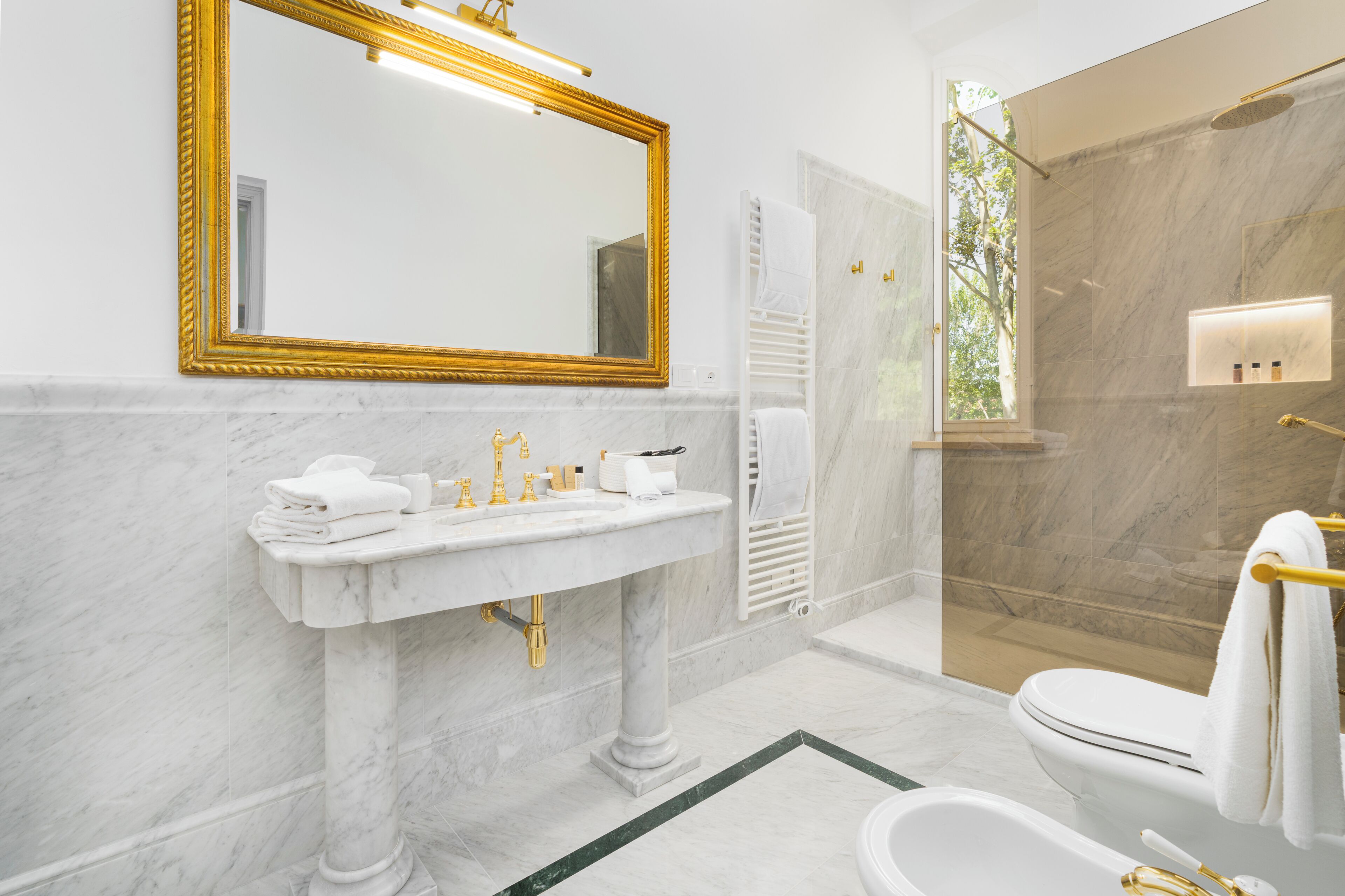 A bathroom with a marble sink, a large mirror, a toilet, and a shower area.