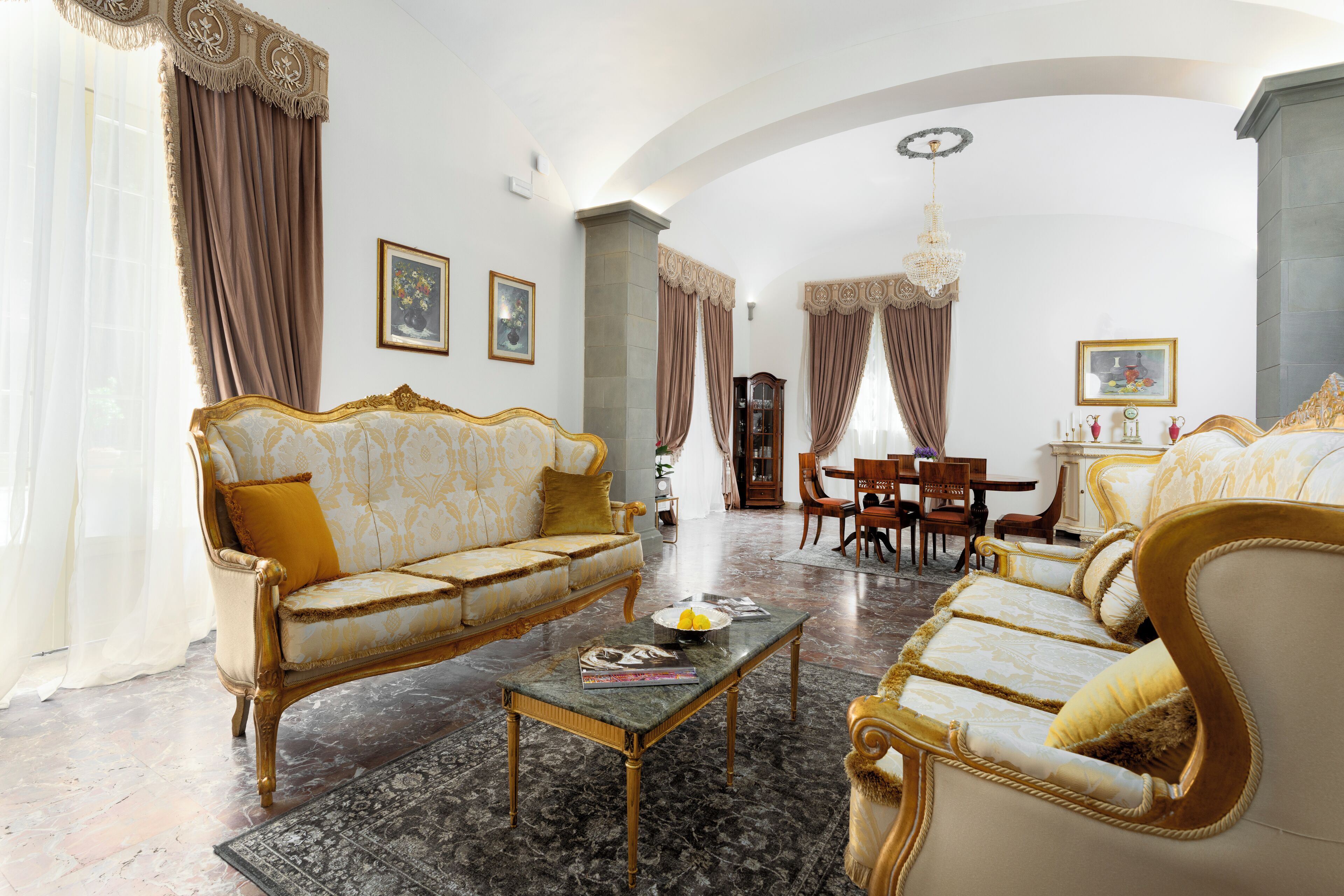 A spacious living room with a large sofa, a coffee table, and a dining area with chairs and a table.