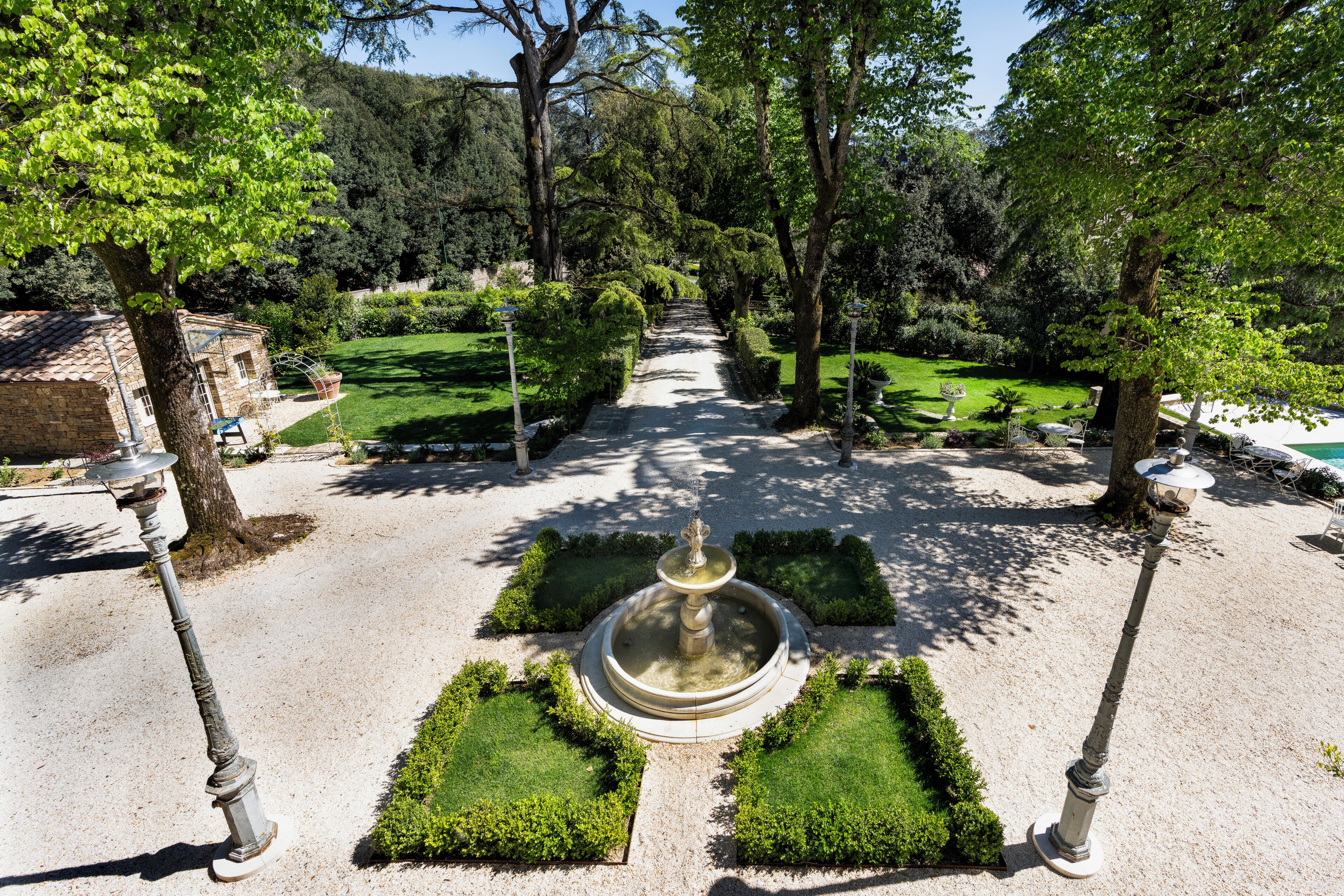 A garden with a central fountain, surrounded by neatly trimmed hedges and trees.