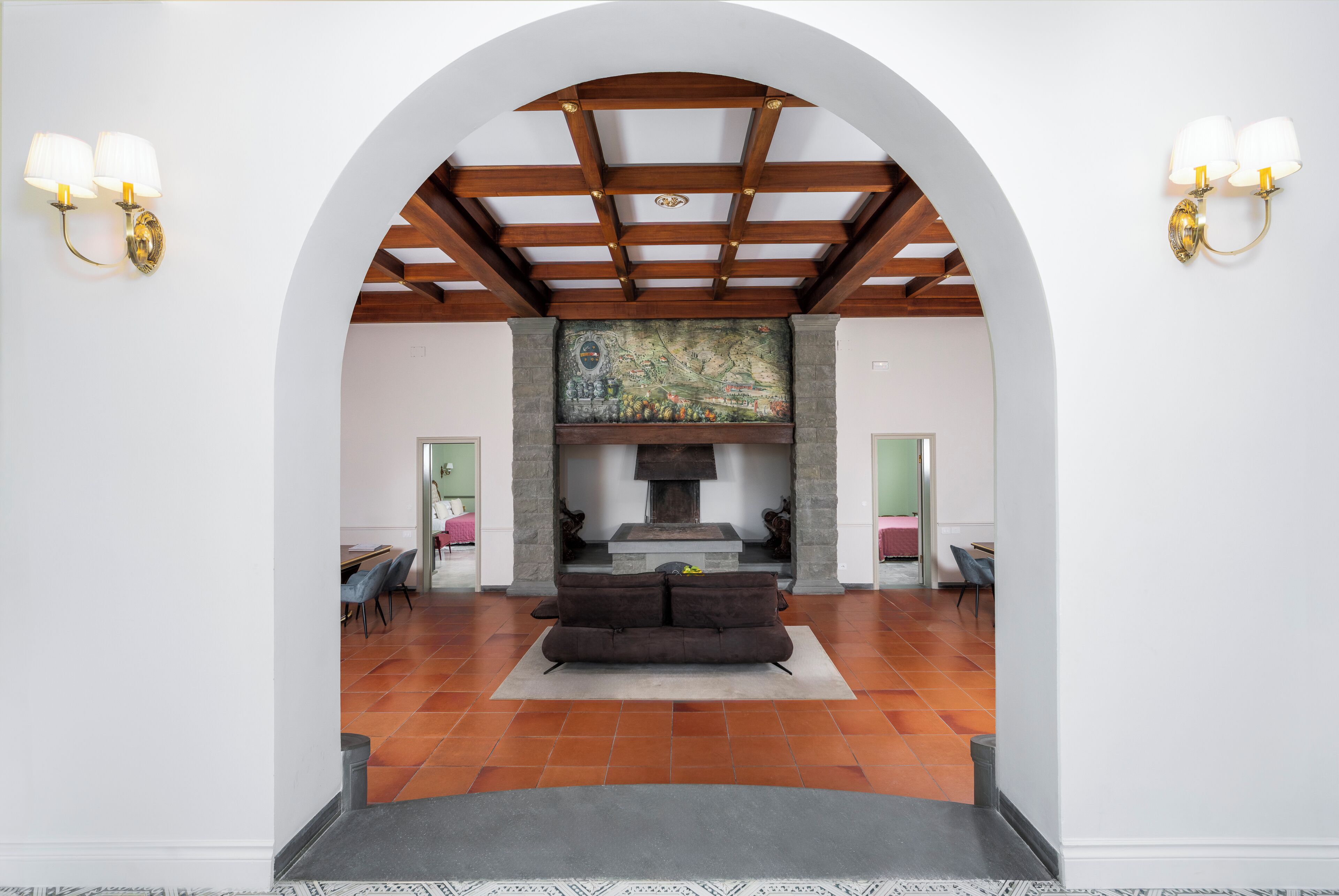 An arched doorway leading to a living area with a fireplace, a sofa, and two wall sconces.