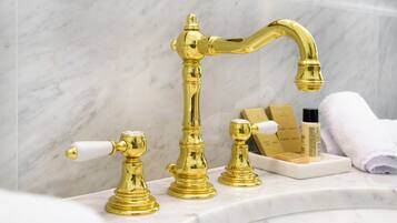 Un bagno con rubinetto dorato, piano di lavoro in marmo e articoli da toilette.