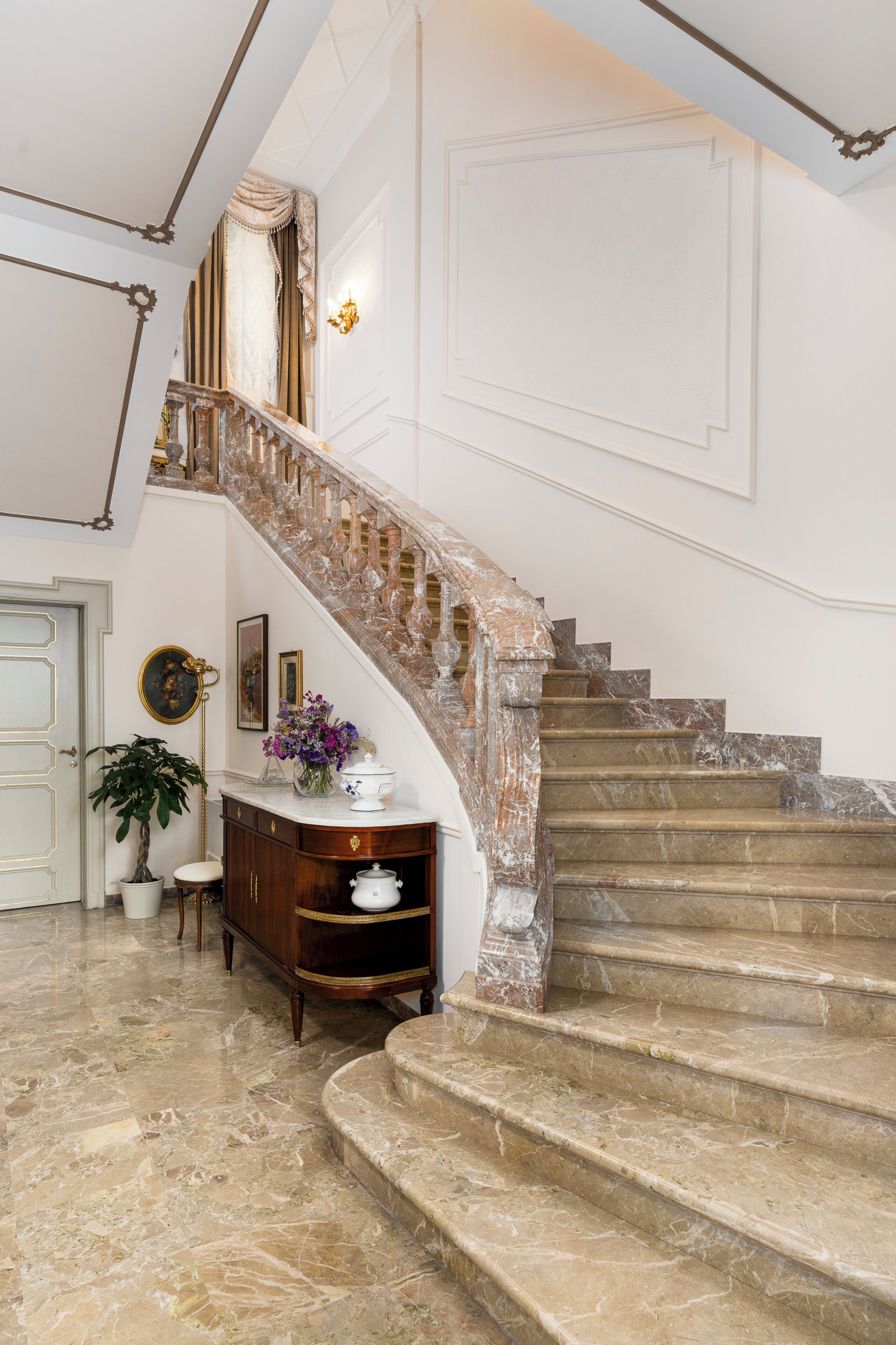 A grand staircase with marble steps and a decorative handrail, leading to an upper floor.