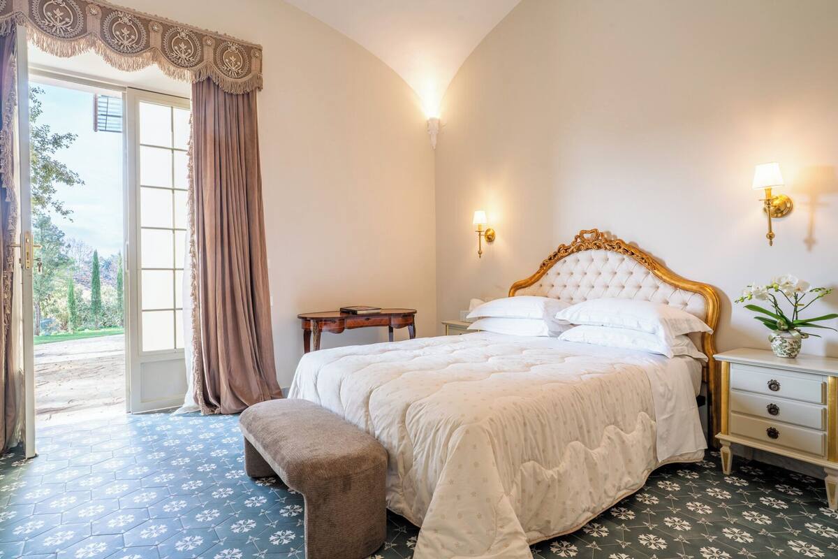 Ein Schlafzimmer mit einem großen Bett, einer Bank, einem Nachttisch und einer Wandlampe.
